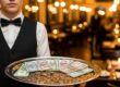 Garçom segurando bandeja com gorjetas em restaurante, simbolizando direitos e rateio justo.